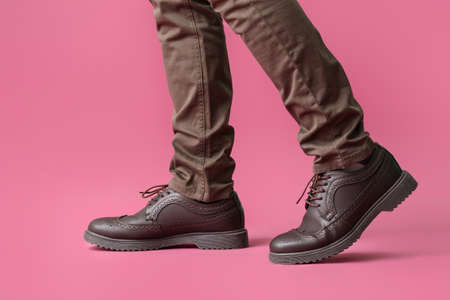 Young man in stylish shoes on color backgroundの写真素材