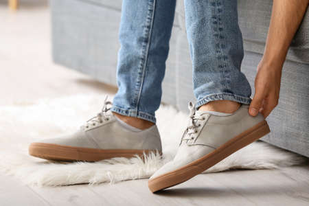Young man putting on stylish shoes