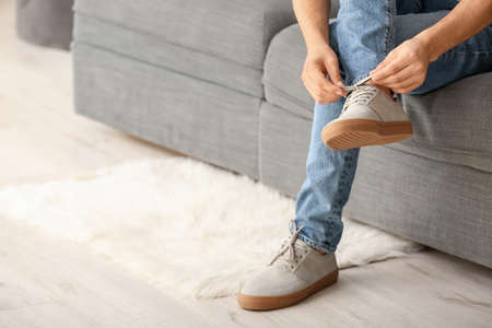 Young man putting on stylish shoes
