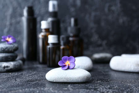 Spa stones with flower and cosmetics bottles on dark backgroundの写真素材