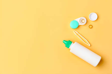 Container with contact lenses, solution and tweezers on color backgroundの写真素材