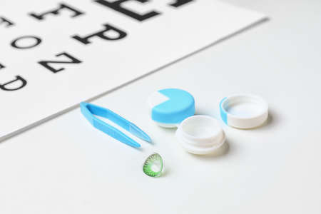 Contact lens with container and tweezers on white background
