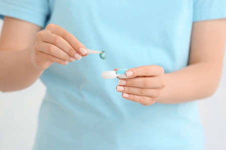 Woman holding tweezers with contact lens and container, closeupの写真素材