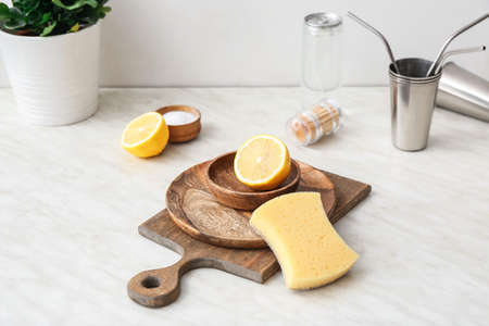 Wooden utensils with sponge and lemon on table in kitchen. Ecology conceptの写真素材