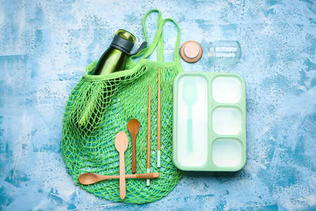 Mesh bag with supplies and lunch box on color background. Ecology conceptの写真素材