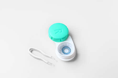 Container with contact lenses and tweezers on white backgroundの写真素材