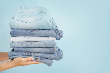Female hands with stylish jeans pants on color background