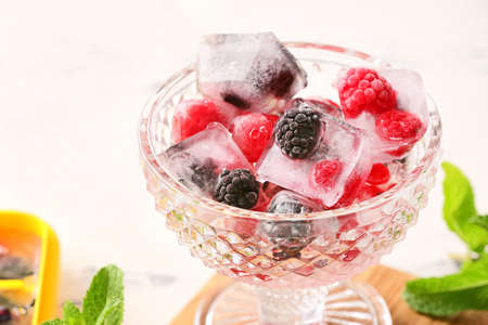 Bowl with ice and frozen berries on table, closeupの写真素材