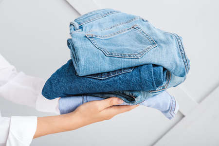 Female hands with stylish jeans pants on gray backgroundの写真素材