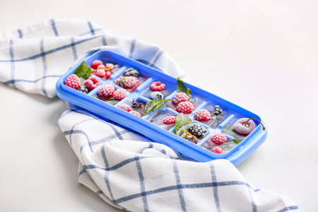 Tray with berries in ice on white backgroundの写真素材