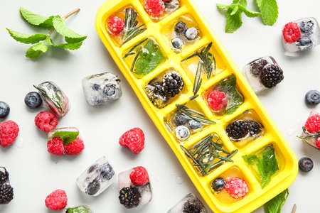 Tray with berries in ice on light backgroundの写真素材