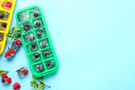 Trays with berries in ice on color backgroundの写真素材