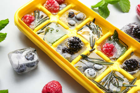 Tray with berries in ice on light backgroundの写真素材