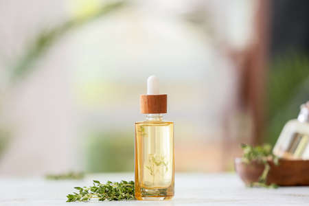 Bottle with thyme essential oil on blurred backgroundの写真素材