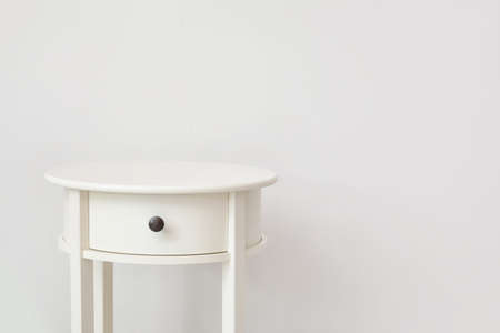 Stylish table with drawer near white wall in room