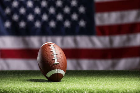 Rugby ball on green grass against national flag of USAの写真素材