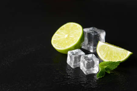 Ice cubes, lime and mint on dark background