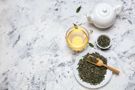 Cup of hot aromatic tea with dry tea leaves on tableの写真素材