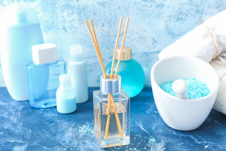 Reed air freshener and blue sea salt in bowl on color backgroundの写真素材
