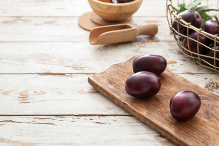 Tasty sweet plums on white wooden background