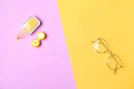 Container with contact lenses, tweezers and eyeglasses on color background