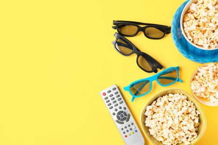 Tasty popcorn, TV remote control and 3D glasses on color backgroundの写真素材