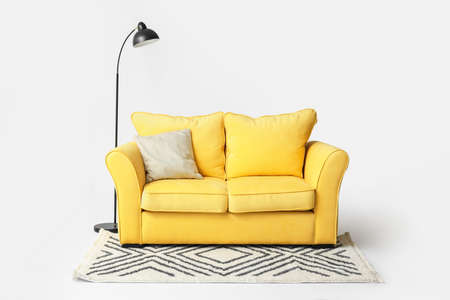 Stylish sofa, carpet and lamp on light backgroundの写真素材