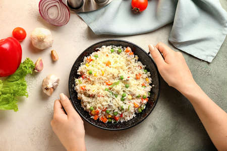 Female hands with tasty pilaf on color backgroundの写真素材