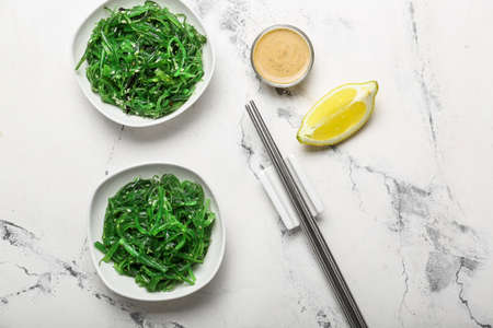 Plates with tasty seaweed salad on white background