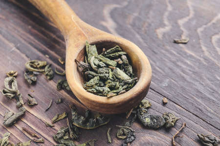 Spoon with dry green tea on wooden backgroundの写真素材