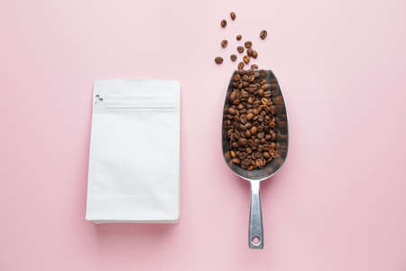 Scoop with coffee beans and bag on color backgroundの写真素材