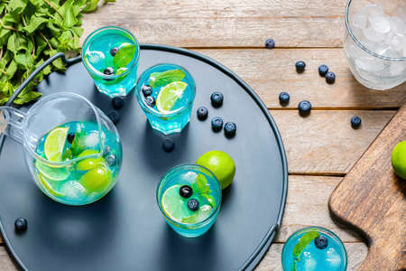 Glasses and jug of tasty blue mojito cocktail on tableの写真素材