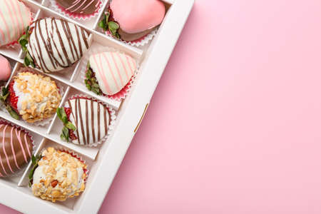 Box with tasty glazed strawberry on color background