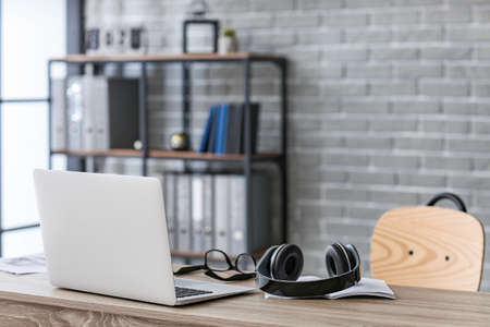 Modern headphones with computer on table in officeの写真素材