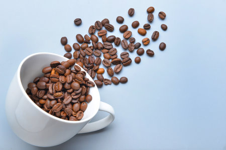 Cup and coffee beans on light background