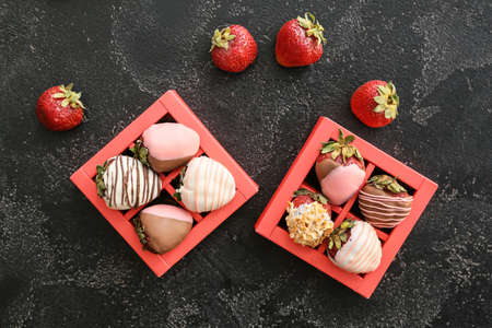 Boxes with tasty glazed strawberry on dark background