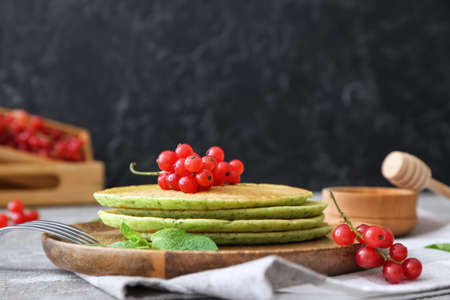 Plate with tasty green pancakes and berries on tableの写真素材