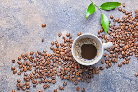 Cup of hot coffee and beans on table