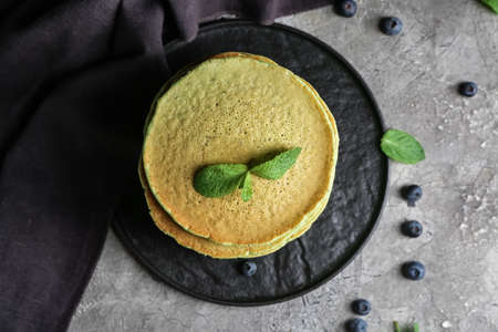 Plate with tasty green pancakes and berries on gray backgroundの写真素材