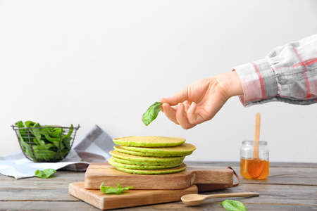 Woman decorating tasty green pancakes on tableの写真素材