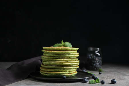 Plate with tasty green pancakes and berries on tableの写真素材