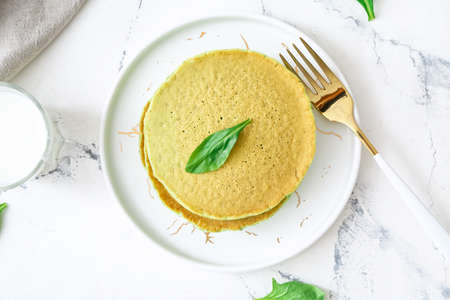Plate with tasty green pancakes on tableの写真素材