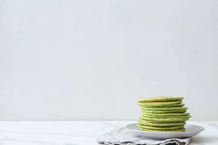 Plate with tasty green pancakes on tableの写真素材