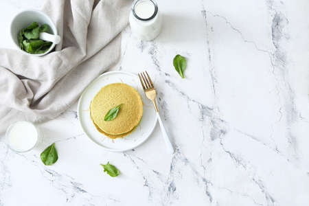 Plate with tasty green pancakes and milk on white background