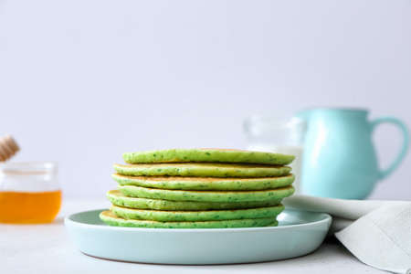 Plate with tasty green pancakes on tableの写真素材
