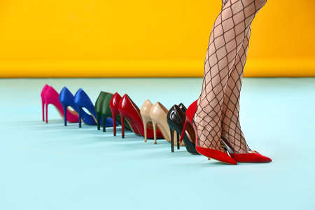 Female legs and many stylish shoes on color backgroundの写真素材