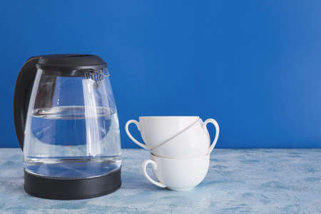 Electric kettle with cups on tableの写真素材