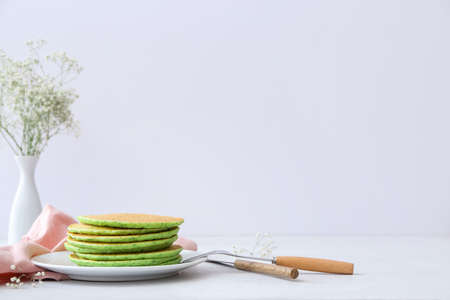 Plate with tasty green pancakes on tableの写真素材