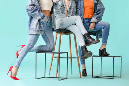 Young women in stylish shoes on color backgroundの写真素材