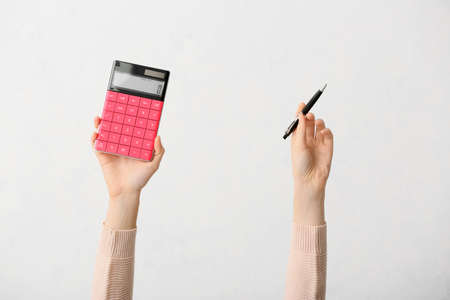 Female hands with calculator and pen on white backgroundの写真素材